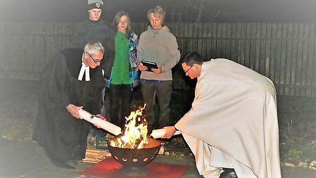 Pfarrer Walter Neunhoeffer (links) und Pfarrer Matthias Bambynek entz&uuml;nden am Osterfeuer die Osterkerze der jeweils anderen Gemeinde. Das Foto entstand im Jahr 2016. Foto: Zimmermann