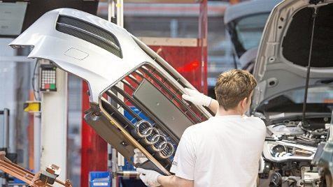 Ein Mitarbeiter montiert im Audi-Werk in Ingolstadt eine Frontpartie. Foto: Armin Weigel, dpa