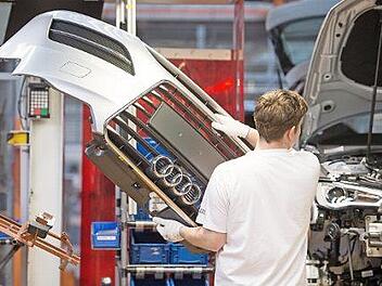 Ein Mitarbeiter montiert im Audi-Werk in Ingolstadt eine Frontpartie. Foto: Armin Weigel, dpa