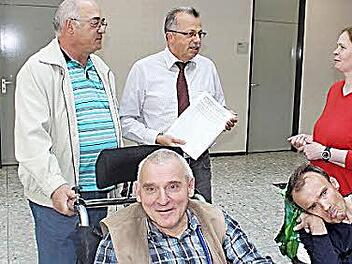 Roland Eyrich (links) und Maria Schüßler überreichten stellvertretendem Landrat Emil Müller ihre Petition zur Einrichtung einer Behinderten-Toilette im Berghaus Rhön. Nutznießer werden auch Robert Nies und Manfred Schüler (im Vordergrund) sein. Foto: Thomas Mäuser
