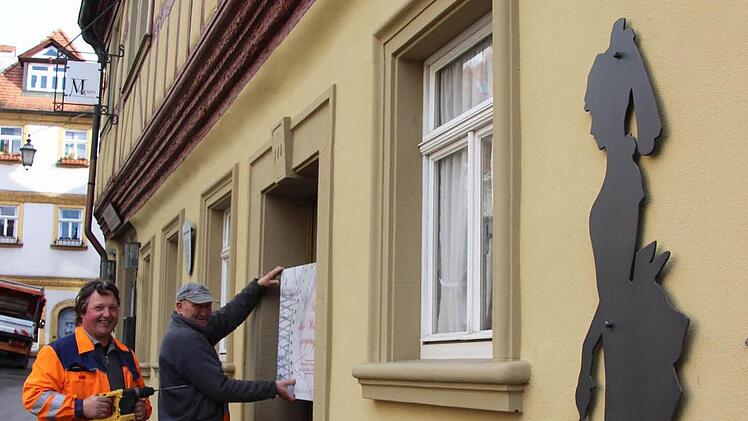 Die beiden Stadtarbeiter Herbert Lechner und Werner Schejbal befestigen das Schild zur Ausstellung an der Tür des Museums.