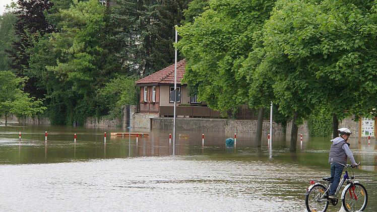 In Haßfurt am Tränkberg nahe dem Main wagt sich ein Radfahrer durch das seichte, nur wenige Zentimeter tiefe Hochwasser.