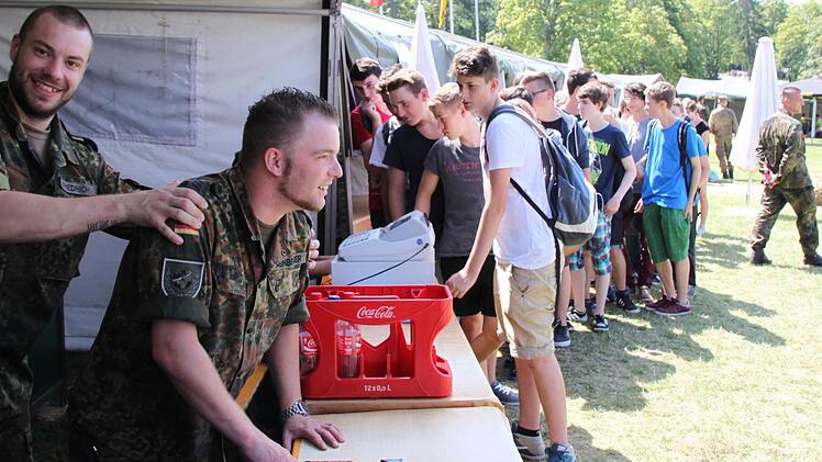 Die Soldaten geben Getränke und Schokoriegel an die Schüler aus.