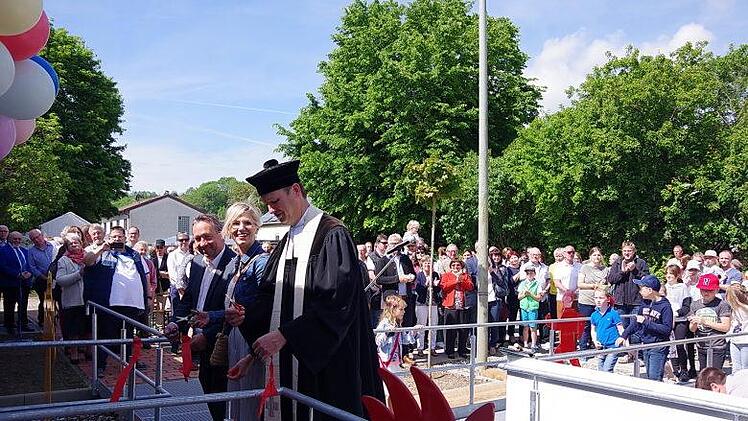Bürgermeister Norbert Gräbner, Kita-Leiterin Stefanie Beiergrößlein und Pfarrer  Andreas Kruater beim symbolischen Durchschneiden der Absperrbande.Heike Schülein