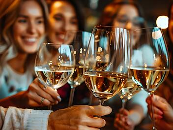 A group of women are holding up wine glasses and smiling
