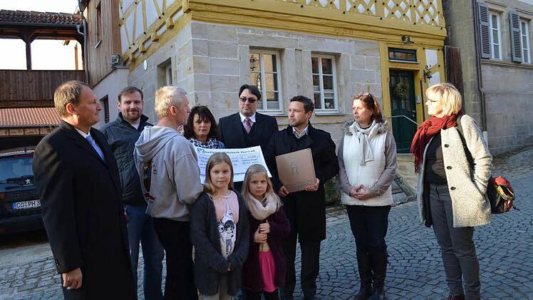 Peter Hofmann zeigt den Gästen anhand einer aufgestellten Fototafel das "Vorher" und "Nachher" der umfangreichen Restaurierung.Das alte Ackerbürgerhaus präsentiert sich im kräftigen roten Ocker.