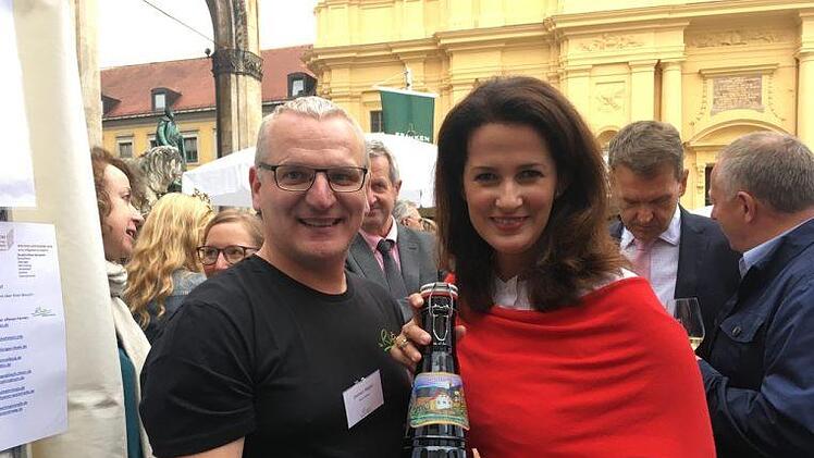 Gerhard N&auml;gler, f&uuml;r Tourismus in Bischofsheim verantwortlich, &uuml;berreicht der bayerischen Landwirtschaftsministerin Michaela Kaniber eine Flasche Kreuzbergbier.Kathrin Kupka-Hahn