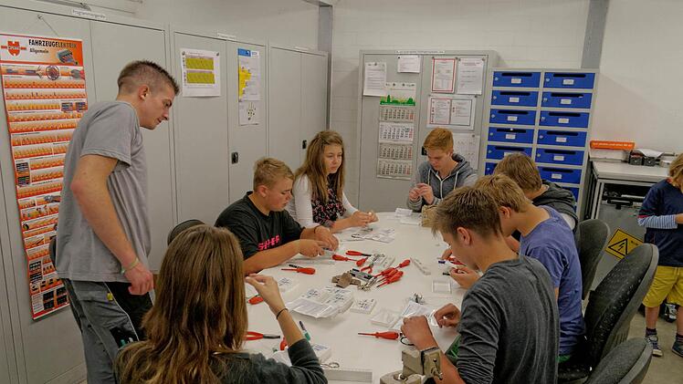 Beim Zusammenbau eines kleinen Elektromotors unterstützte der Auszubildende Tobias Scheiderer (stehend) die Besucher. Foto: GKN