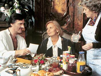 Der "Monaco Franze" (Helmut Fischer) ist im Faschingsfieber - wenig sp&auml;ter wird er mit echtem Fieber im Bett liegen. Ehefrau Annette (Ruth Maria Kubitschek, Mitte) und Haush&auml;lterin Irmgard (Erni Singerl) sind an seine Spinnereien l&auml;ngst gew&ouml;hnt.