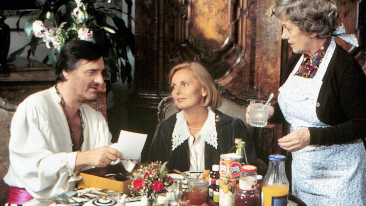 Der "Monaco Franze" (Helmut Fischer) ist im Faschingsfieber - wenig sp&auml;ter wird er mit echtem Fieber im Bett liegen. Ehefrau Annette (Ruth Maria Kubitschek, Mitte) und Haush&auml;lterin Irmgard (Erni Singerl) sind an seine Spinnereien l&auml;ngst gew&ouml;hnt.