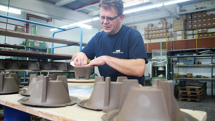 Uwe Hofmann arbeitet im Rödentaler Betriebsteil an der Drehscheibe. Dort entstehen Keramikteile aus dunklem Granitium, wie hier das sogenannte Schmelzfeuer.  Fotos: Helke Renner