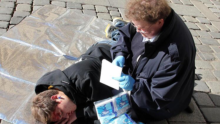 Kerstin Lange packt eine Zellstoff-Mull-Kompresse als sterile Wundauflage aus. In einem Verbandpäckchen ist übrigens auch eine Kompresse, die schon an einer Mullbinde befestigt ist, enthalten. Ein Verband ist allerdings bei einem liegenden Patienten schwieriger anzubringen.