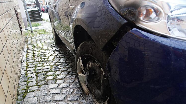 An einer Straße ist noch eines der beschädigten Autos zu sehen.Foto: Arkadius Guzy
