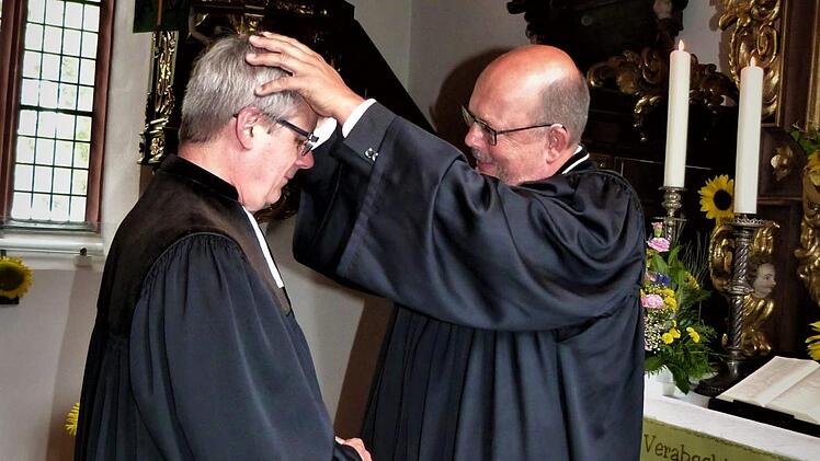 Mit herzlichen Worten wurde Pfarrer Jürgen Harder von Dekan Thomas Kretschmar (rechts) verabschiedet, der ihn hier für seine künftige Aufgabe segnet. Foto: Werner Reißaus
