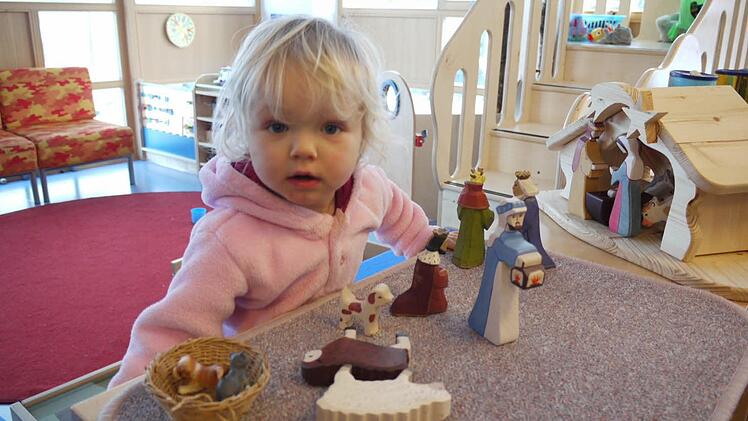 Die zweijährige Freya schaut sich die Figuren aus der Weihnachtskrippe ganz genau an. Die Holzfiguren im Montessori-Kinderhaus gefallen ihr.   Fotos: Pauline Lindner