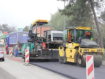 Mit vier Metern pro Minute bewegt sich die Asphaltierungsmaschine vorwärts. Ein Laster nach dem anderen entlädt seine Fracht in den Aufnahmebehälter. Walzen verdichten die Binderschicht. Foto: Friedwald Schedel