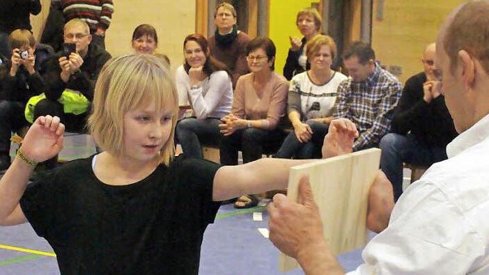 Voll konzentriert ist Hannah Unglaub bereit, das Holzbrett durchzuschlagen. Mit im Bild (rechts) Kursleiter Fred Busse. Foto: Schule