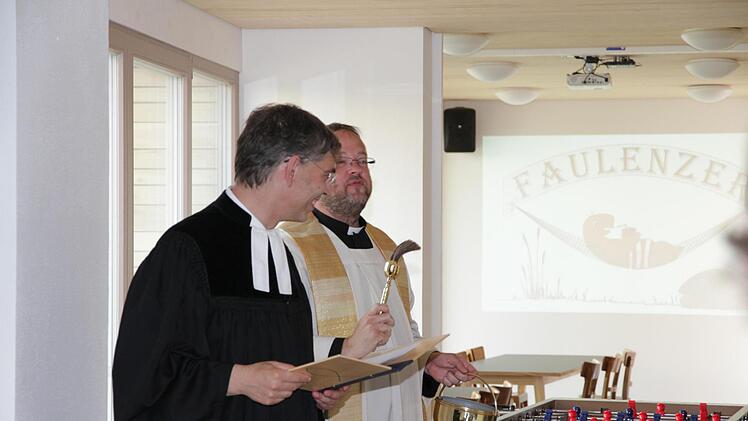 Die beiden Pfarrer Daniel Schuster und Christian Muschler (links) segnen den Dorftreff Eggolsheim. Foto: Mathias Erlwein