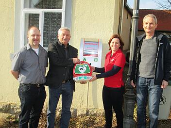 Jürgen Müller, Bürgermeister Peter Hart, Sabina Jaborek-Hugo und Bereitschaftsarzt Markus Full präsentieren den Defibrillator am Heimatmuseum in Fuchsstadt.  Foto: Winfried Ehling