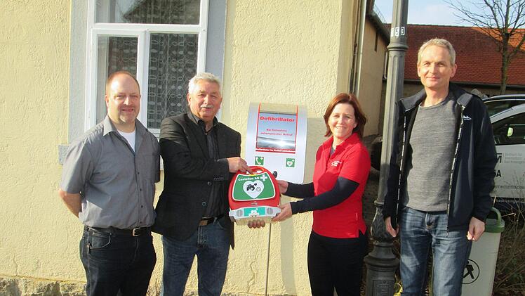 Jürgen Müller, Bürgermeister Peter Hart, Sabina Jaborek-Hugo und Bereitschaftsarzt Markus Full präsentieren den Defibrillator am Heimatmuseum in Fuchsstadt.  Foto: Winfried Ehling