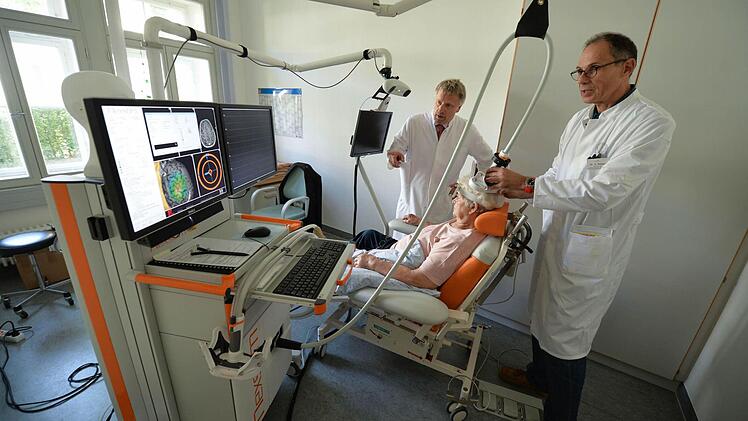 Hermann Weber (rechts) platziert die Spule zur Magnetstimulation auf dem Schädel der Patientin, während Peter Rieckmann die Navigation auf dem Bildschirm verfolgt. Foto: Ronald Rinklef