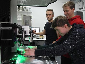 Philipp Muth bei der Arbeit an der Lasermaschine mit Produktionsleiter Simon Schlee (M.) und Wirtschaftspaten Adrian Dümpert (hinten)