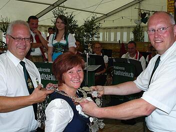 Kommissar Stefan Sigmund (links) und 1. Schützenmeister Frank Wunner (rechts) legen Beate Sigmund (Bildmitte) die Königkette an. Fotos: Klaus-Peter Wulf