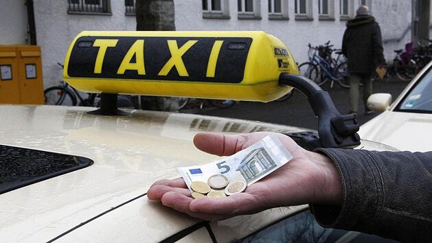 Ein Taxifahrer zeigt, welcher Stundenlohn ihm k&uuml;nftig zusteht. Foto: Peter Groscurth