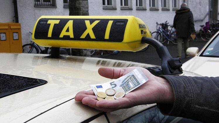 Ein Taxifahrer zeigt, welcher Stundenlohn ihm künftig zusteht. Foto: Peter Groscurth