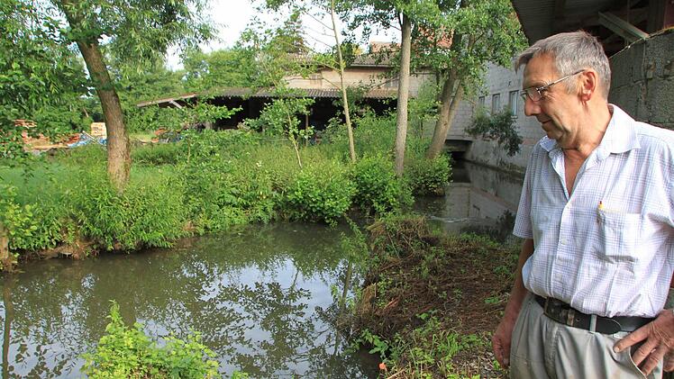 Rudolf Halbig steht am Mühlenkanal. Der ist zwar gefüllt, aber die Fließgeschwindigkeit ist durch die Trockenheit viel zu niedrig. Dadurch produziert das Wasserkraftwerk in der Mühle deutlich weniger Strom als üblich.