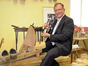 Bezirkstagspräsident Erwin Dotzel hat auf einer historischen Schuster-Werkbank Platz genommen, die auch bei den kommenden unterfränkischen Kulturtagen in Bad Brückenau zu sehen sein wird. Foto: Julia Raab