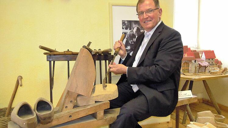 Bezirkstagspräsident Erwin Dotzel hat auf einer historischen Schuster-Werkbank Platz genommen, die auch bei den kommenden unterfränkischen Kulturtagen in Bad Brückenau zu sehen sein wird. Foto: Julia Raab