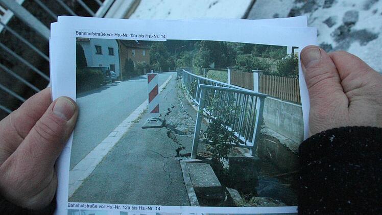 Bürgermeister Norbert Gräbner zeigt ein Bild, wie die schiefe Mauer vor der Sanierung aussah.  Foto: Friedwald Schedel