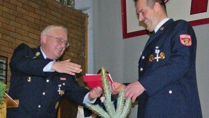 F&uuml;r den FW-Patenverein Kronach &uuml;bergibt Gottfried Weller (links) Pr&auml;sent und Jubil&auml;umsb&auml;umchen (im Vordergrund) an Vorsitzenden Ulli Poehlmann Foto: oso