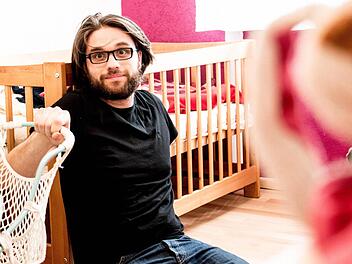 Florian Herrnleben sitzt geschafft vor dem Kinderbett. Antonia als Vertreterin der fünften Generation der Puppenbühne Herrnleben schlummert währenddessen friedlich.  Foto: Pia Nagel