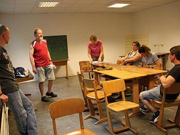 Abgewetzter Fußboden, Holzmöbel und eine Tafel: Am Raum, in dem die Stadt in Zukunft einen Anlaufpunkt für Jugendliche anbieten will, ist noch so gut wie nichts gemacht worden. Hier treffen sich die Verantwortlichen von InJusa (Integragtionsbezogene Jugendsozialarbeit). Foto: Ulrike Müller