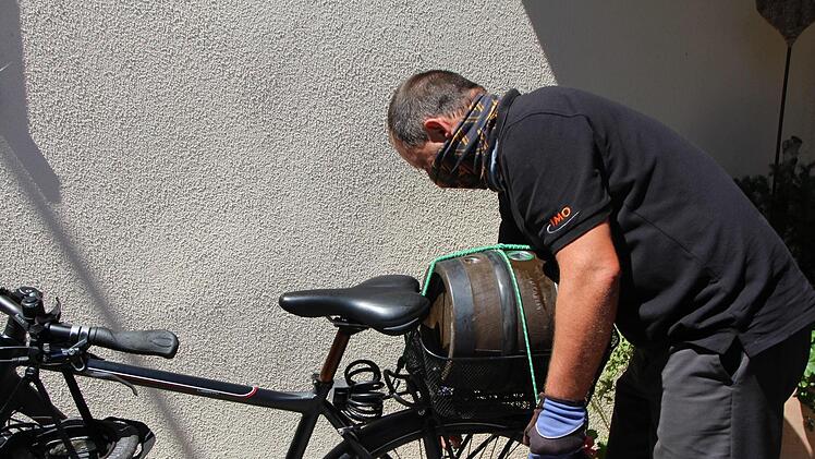 Winfried Geyer schnallt das Fass auf sein Fahrrad. Foto: Niklas Schmitt