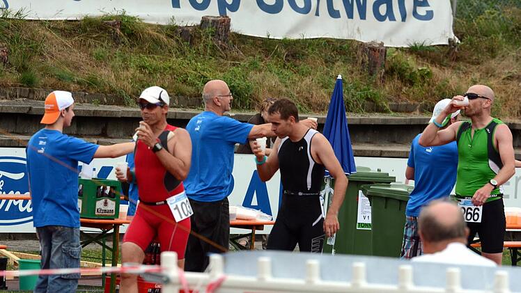 Guido Seeger vom Baiersdorfer SV (rot) stärkt sich unterwegs mit einem Becher Wasser. Das Erlanger Bier im Hintergrund gab es - wenn überhaupt - erst nach dem Triathlon, den Seeger als 97. auf der Kurzdistanz beendete, zu trinken.  Foto: herzopress