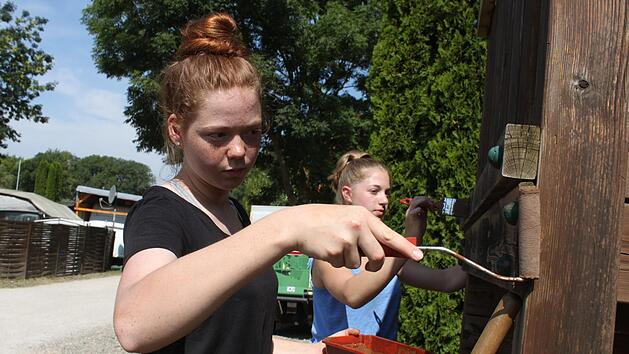 Damit die Sch&uuml;ler kostenlos auf dem Campingplatz schlafen d&uuml;rfen, packen sie beim Renovieren des Spielplatzes mit an. Aliyah und Johanna streichen hier gerade das Spielger&auml;t. Fotos: Sarah Stieranka