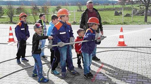Fast schon wie die Großen spritzen die Kinder mit dem Wasserschlauch.