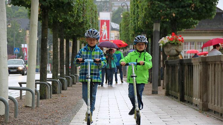 Niklas (links) und Elias lassen sich den Urlaub in Bad Kissingen nicht vermiesen. Mit Regenjacke lässt sich prima Roller fahren. Foto: K. Kupka-Hahn
