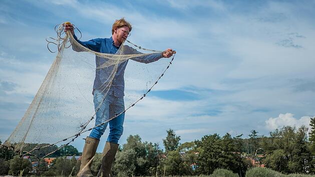 Louis Grimmer wirft sein Netz aus. Die Fischzucht am Alten Kurhaus in Trabelsdorf ist einer von &uuml;ber 100 Direktvermarktern in Stadt und Landkreis Bamberg.  Foto: Lea Schreiber