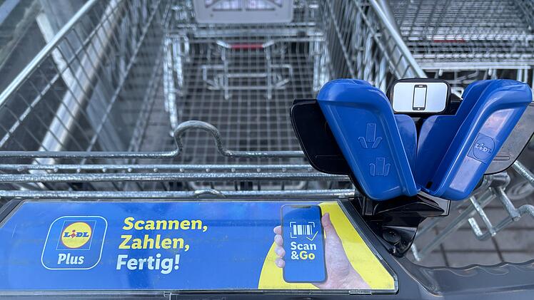 Ein Einkaufswagen mit einem "Scan & Go"-System von Lidl. Es zeigt eine Halterung und Werbung, die schnelles Einkaufen durch Scannen und Bezahlen per App erm&ouml;glicht.