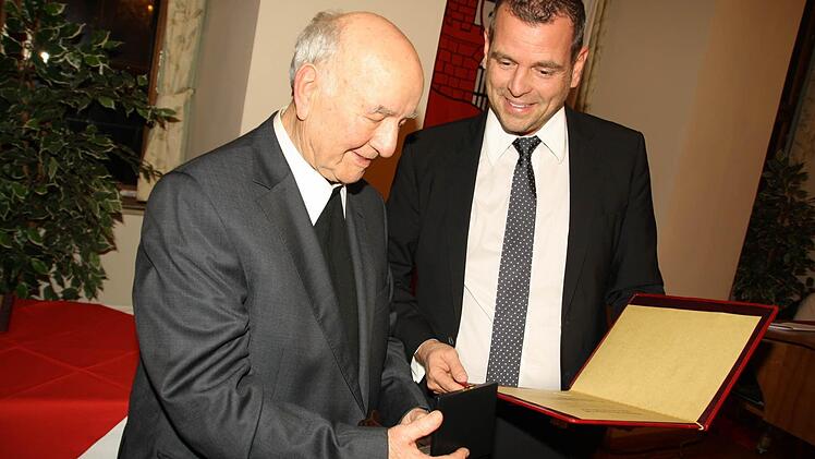 Pfarrer Heinrich Mitka erhält von Bürgermeister Anton Schick jun. die Silberne Bürgermedaille. Foto: Foto: Paul Ziegler