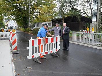 Während Bauhofmitarbeiter Ralf Jörg die letzten Barrikaden zur Brückenfreigabe aufräumt, informiert Bauamtsleiter Jürgen Fenner (Mitte) Bürgermeister Egon Herrmann (rechts) über durchgeführte Maßnahmen und beide geben die Durchfahrt über die Brücke frei.  Foto: Karl-Heinz Hofmann