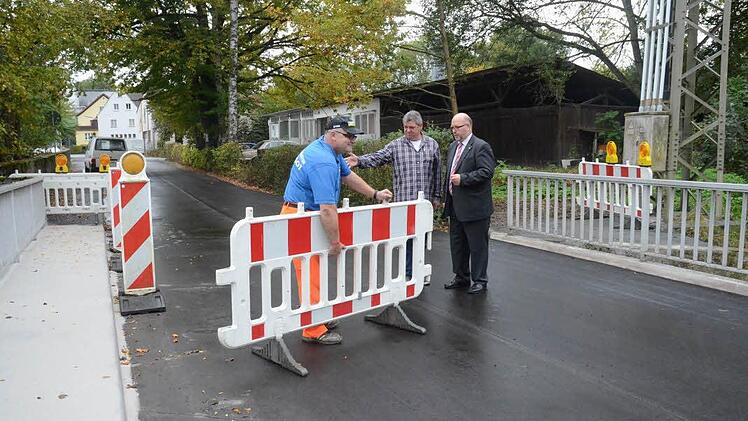 Während Bauhofmitarbeiter Ralf Jörg die letzten Barrikaden zur Brückenfreigabe aufräumt, informiert Bauamtsleiter Jürgen Fenner (Mitte) Bürgermeister Egon Herrmann (rechts) über durchgeführte Maßnahmen und beide geben die Durchfahrt über die Brücke frei.  Foto: Karl-Heinz Hofmann