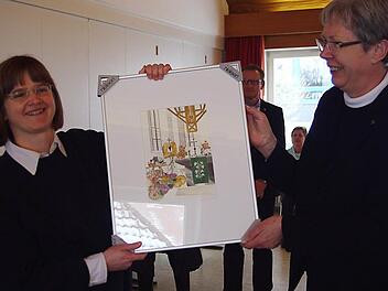 Dekanin Dorothea Richter (r.) überreichte Pfarrerin Susanne Treber als Abschiedsgeschenk ein Aquarell von Peter M. Bannert. Foto: Heike Schülein