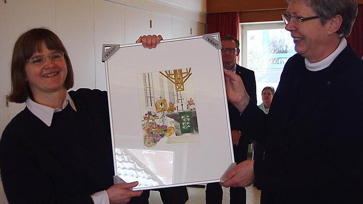 Dekanin Dorothea Richter (r.) überreichte Pfarrerin Susanne Treber als Abschiedsgeschenk ein Aquarell von Peter M. Bannert. Foto: Heike Schülein