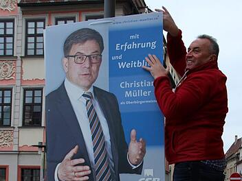 Thomas Baumann hängt am Marktplatz ein Plakat seines CSB-Kollegen und OB-Kandidaten Christian Müller auf.Foto: Oliver Schmidt