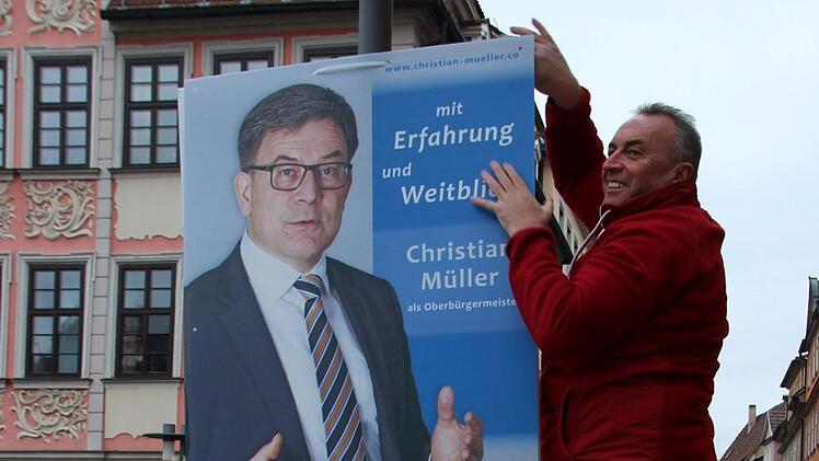 Thomas Baumann hängt am Marktplatz ein Plakat seines CSB-Kollegen und OB-Kandidaten Christian Müller auf.Foto: Oliver Schmidt